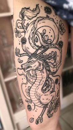 a black and white photo of a dragon with flowers on it's leg,