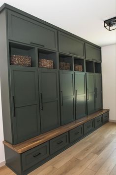 an empty room with green cupboards and drawers on the wall, in front of a wooden floor