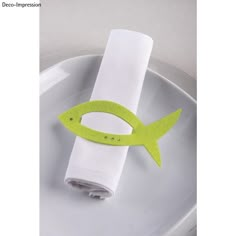 a fish napkin holder on a plate with a white cloth and green trim around it