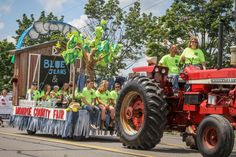 people riding on the back of a red tractor down a street in front of a crowd