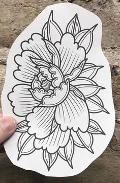 a hand holding up a sticker with an image of a flower in the middle