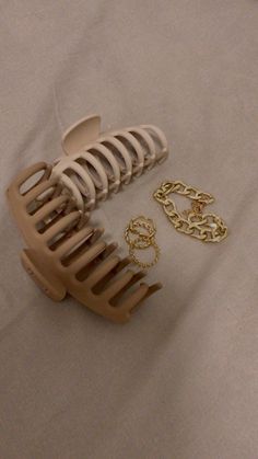 a hair comb and two pairs of gold chains on a white sheet with a pair of scissors