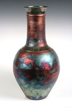 an artistic vase is shown on a white background with red, blue and green designs