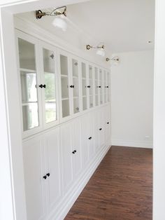 an empty room with white cabinets and wood floors