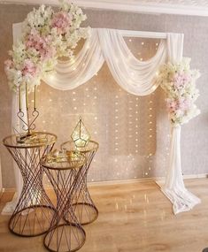 two tables with vases and flowers on them in front of a curtained window