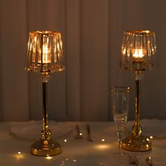 two candles are lit on the table with silverware and glasses in front of them