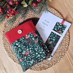 two envelopes are sitting next to each other on a table with holly and red ribbon