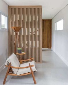 a white chair sitting in front of a wooden wall with vertical slats on it