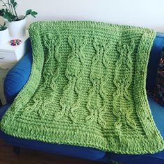 a green knitted blanket sitting on top of a blue couch