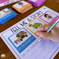 a hand holding a pencil over a book with pictures on it and other children's books in the background