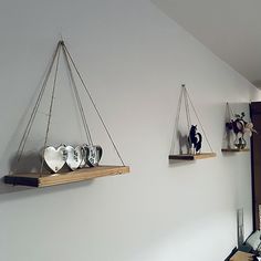 three hanging shelves on the wall with vases and other decorative items in front of them