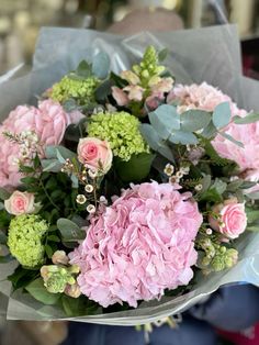 a bouquet of pink and green flowers in someone's hand