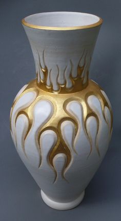 a white and gold vase sitting on top of a table