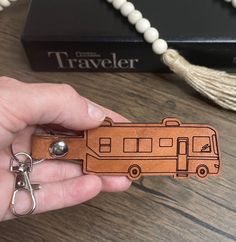 a hand holding a wooden keychain with a bus design on the front and side