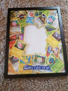 a photo frame filled with lots of different pokemon cards on the floor next to a carpet