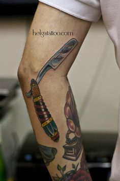 a person with a tattoo on their arm holding a knife in one hand and an object in the other