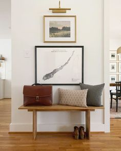 a wooden bench sitting in the middle of a living room next to a wall with pictures on it