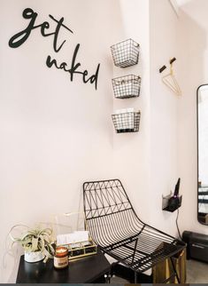 a black chair sitting in front of a mirror on top of a wooden table next to a wall