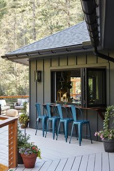 a deck with blue chairs and potted plants on the side of it next to a bar