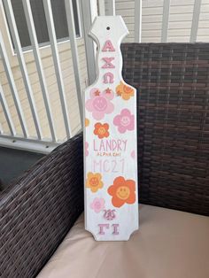 a wooden sign with flowers and letters on it