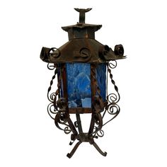 an old fashioned lamp with blue glass and iron work on the top, against a white background