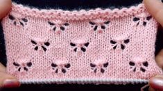 someone is holding up a pink knitted item with small flowers on the front and sides