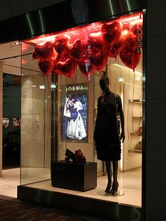 a window display with red heart shaped balloons