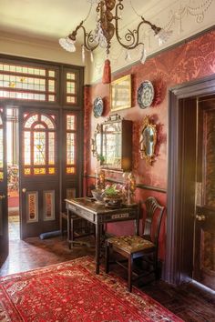 an ornately decorated entryway with red walls and rugs, chandelier and mirror