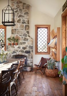 a dining room table and chairs in front of a stone wall with potted plants