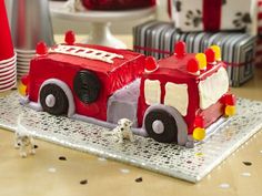 a cake shaped like a firetruck on a table with red and white decorations