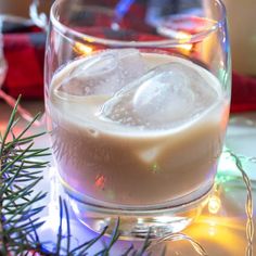 two glasses filled with ice sitting on top of a table next to a christmas tree