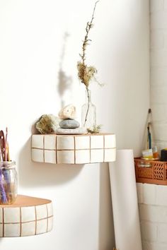 two shelves with vases and other items on them in a white walled room next to a brick wall