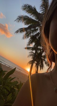 a woman standing on top of a sandy beach next to the ocean with palm trees