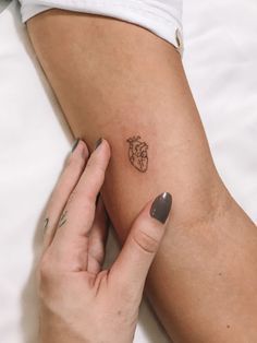 a woman's arm with a heart tattoo on the left side of her body