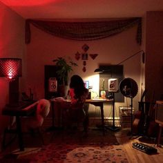 a woman sitting at a desk in a dark room with red lights on the walls