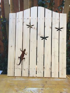 a wooden fence with two metal lizards on it's sides and one lizard running across the fence