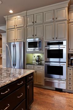 a kitchen with two ovens and an island in front of the stove, refrigerator and microwave