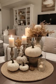 a table topped with white pumpkins and candles