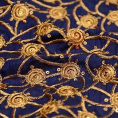 gold and blue embroidered fabric with flowers on the side, close up photo taken from above