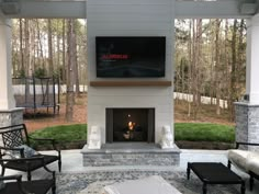 an outdoor fireplace and seating area with television on the wall