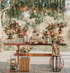 an outdoor table with flowers and greenery on it, along with other decorations in vases