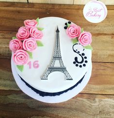 a white cake with pink roses and the eiffel tower