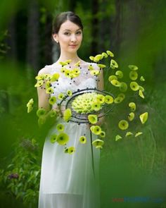 a woman in a white dress holding a basket filled with yellow flowers and greenery