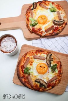 two pizzas sitting on top of wooden cutting boards next to a cup of coffee