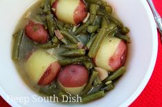 a white bowl filled with green beans and potatoes on top of a red table cloth