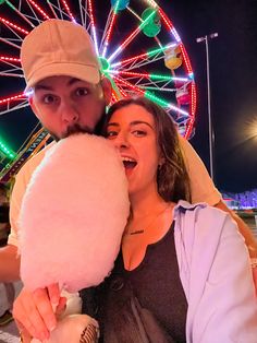 a man and woman posing for a photo in front of a ferris wheel