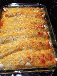 a casserole dish sitting on top of a stove with cheese and meat in it