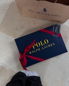 a person's feet in black and white shoes next to a blue box with the polo logo on it