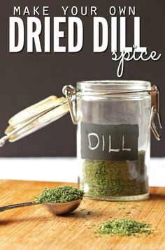 a jar filled with dried dill on top of a wooden table next to a spoon