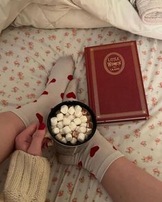 a person is holding marshmallows in front of a book on a bed